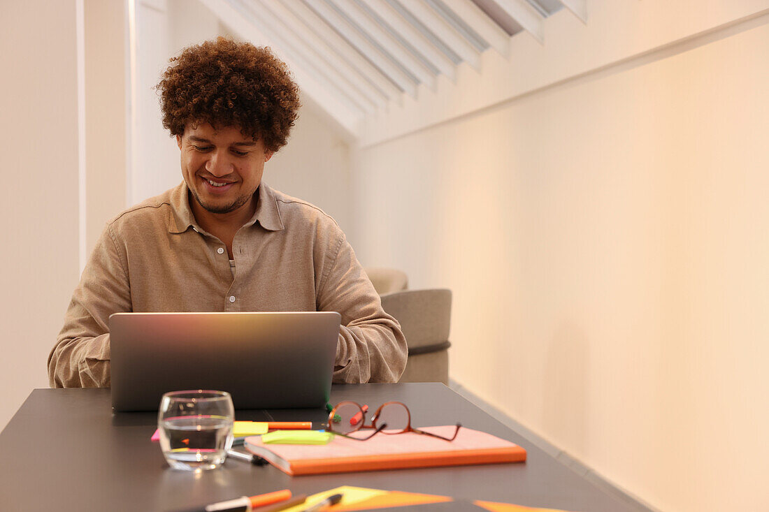 Smiling man with laptop at table in office