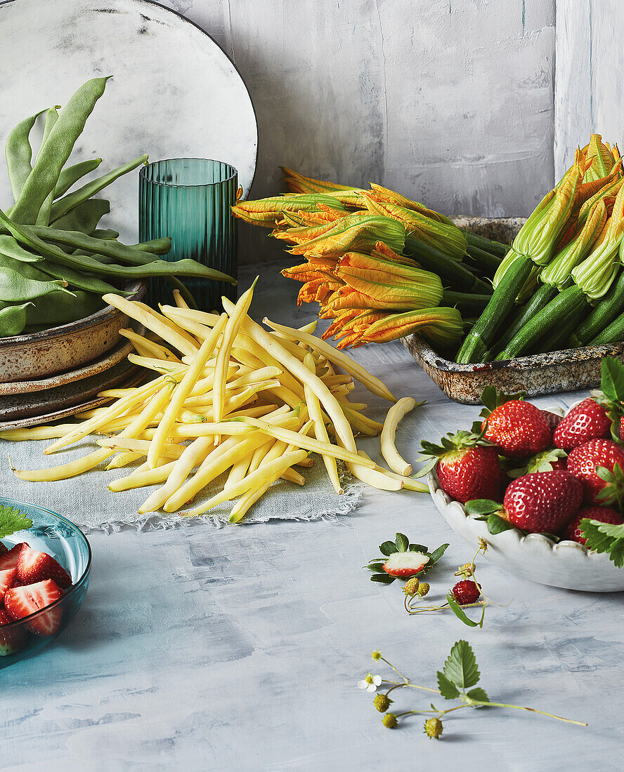 Stillleben mit gelben und grünen Bohnen, Zucchiniblüten und Erdbeeren