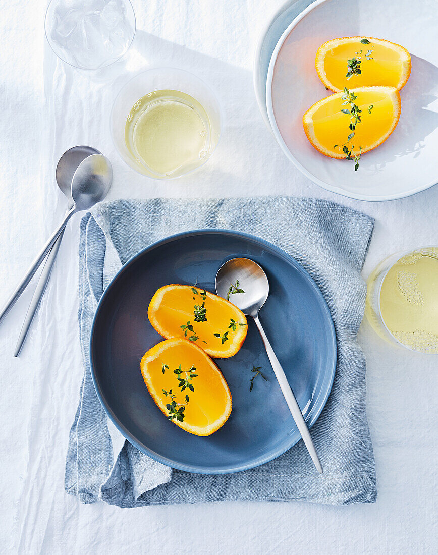 Halbierte, frische Orangen mit Thymianzweigen