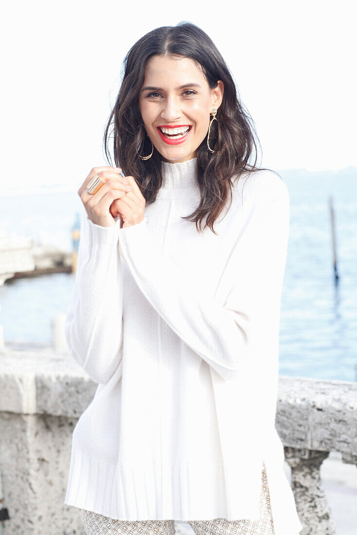 Long-haired young woman in white turtleneck jumper, laughing, red lipstick