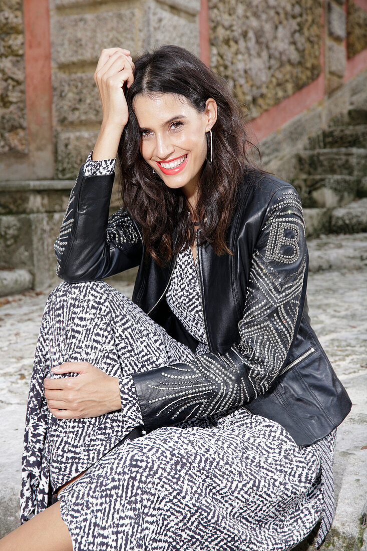 Long-haired young woman in black and white patterned skirt and leather jacket with embroidery