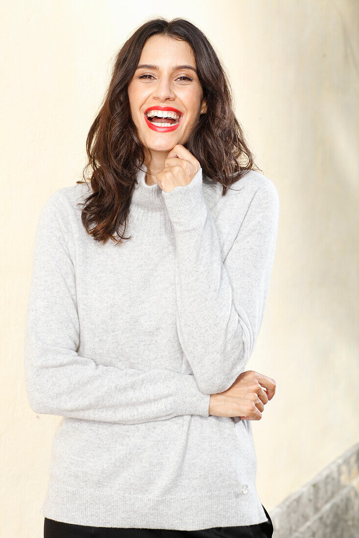 Long-haired young woman in white turtleneck jumper, laughing, red lipstick