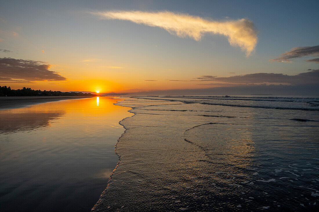 Sunset on the beach in Las Lajas, Panama. People walk on the beach silhouetted.