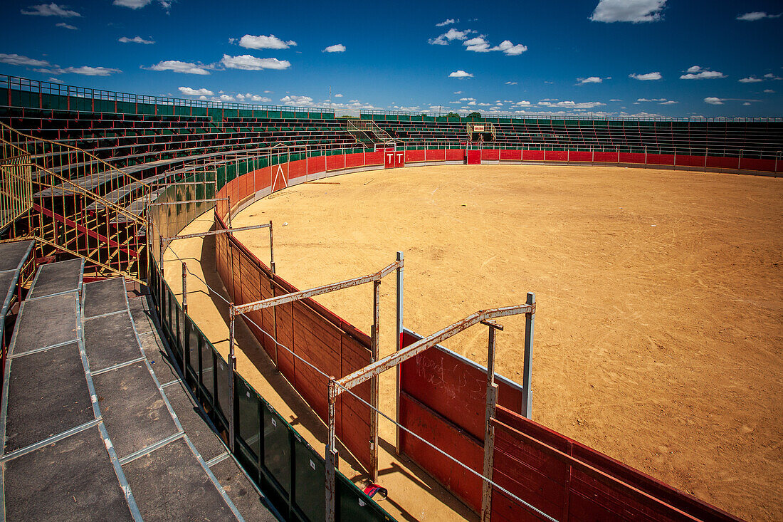 A panoramic view of an empty portable bullring in Aznalcazar, Sevilla, Spain, showcasing the traditional arena under a vivid blue sky.