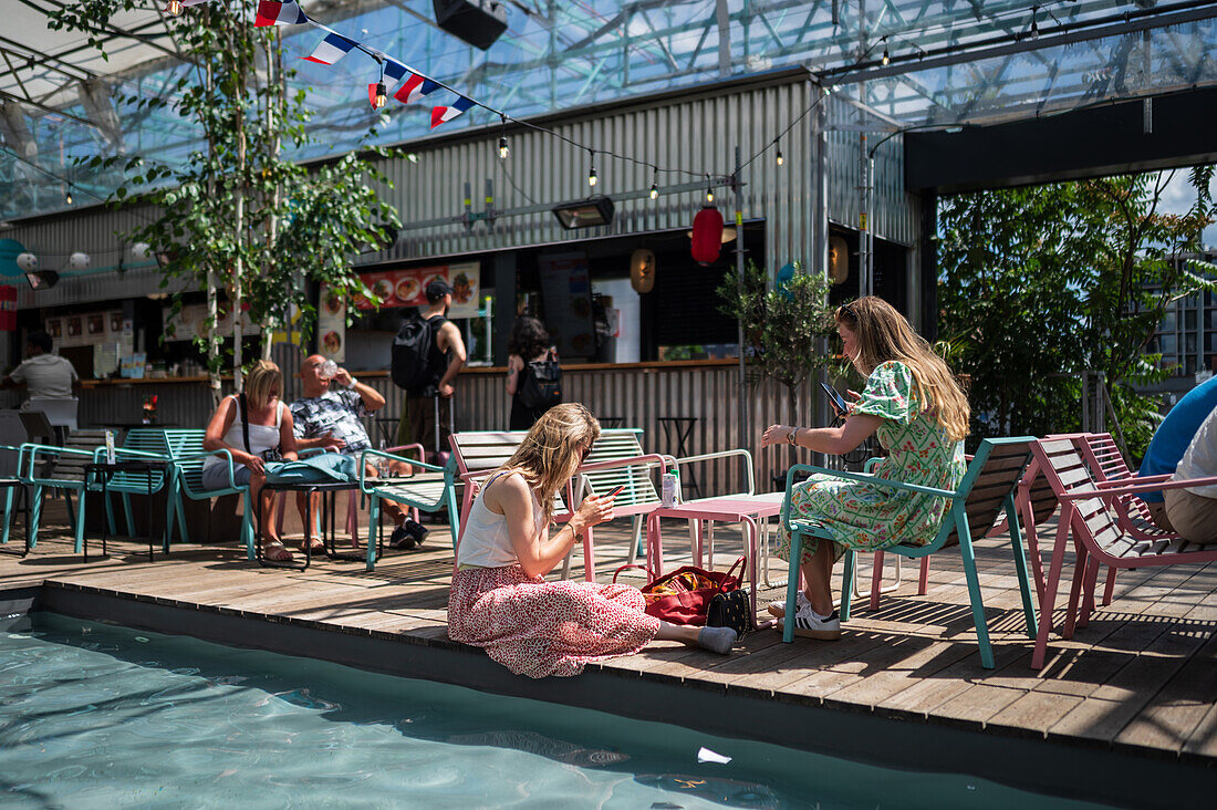 Kunden erfrischen sich am Pool auf dem Manifesto Market, einem kulturellen Erlebnis im Herzen Prags mit Pop-up-Designerlebnisbars und hochwertigem Street Food