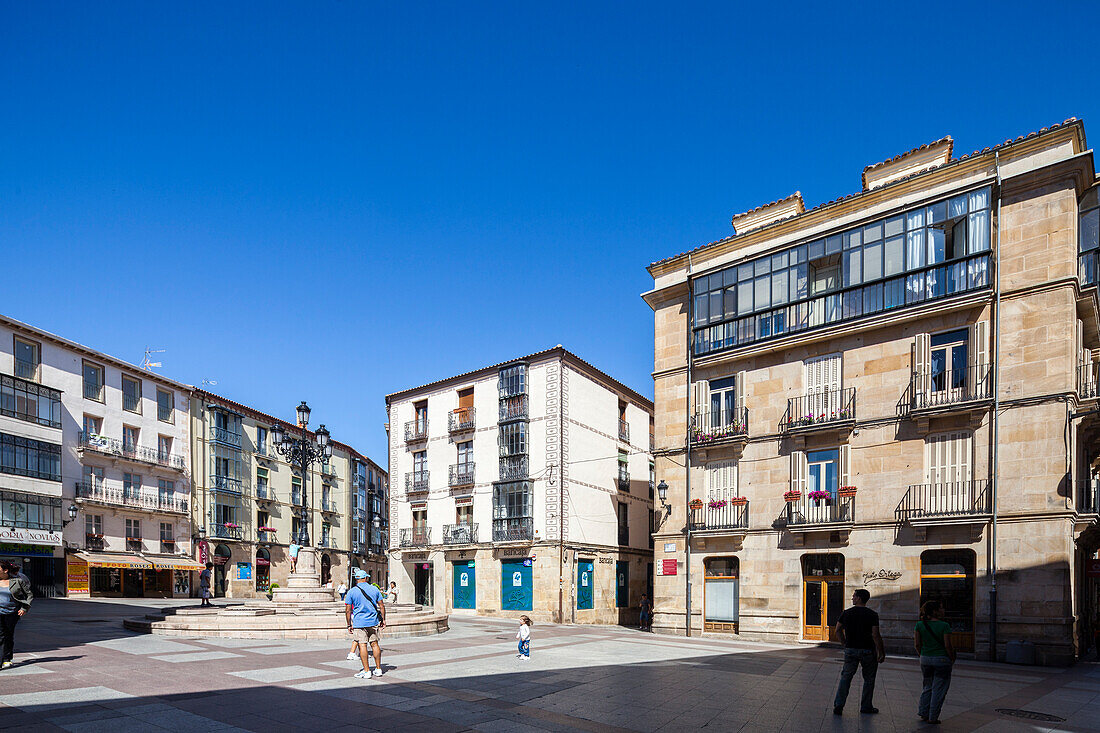 Soria, Spain, Aug 13 2009, A wide shot of a plaza in Soria, Spain, with several people walking around. The plaza is surrounded by buildings, some of which have balconies