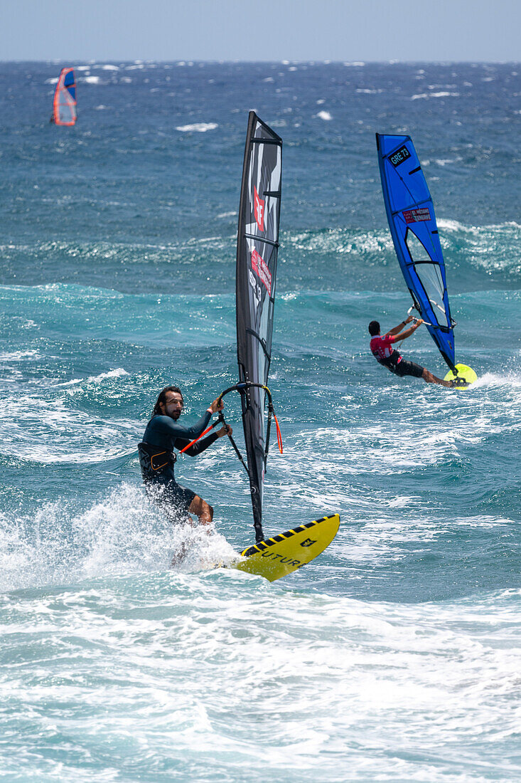 Participants compete in the Windsurfing World Championship in El Medano, Tenerife, Spain, showcasing thrilling skills and vibrant energy on the waves.