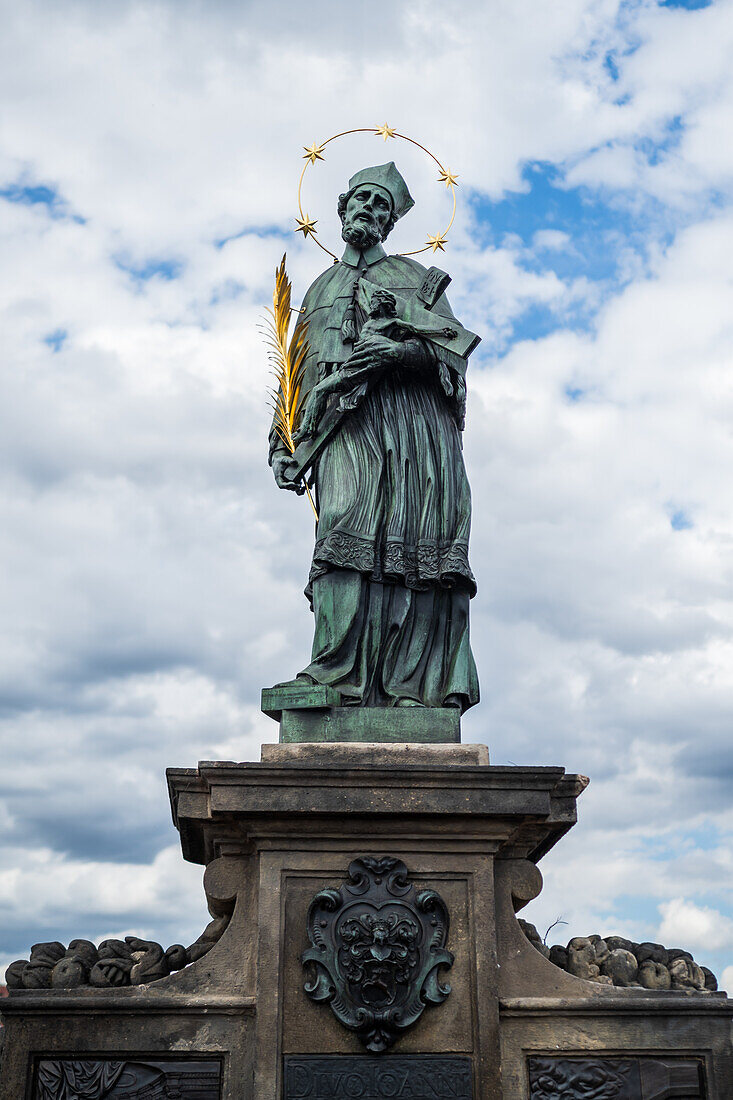 Tourists touching a plaque that is part of the statue St. John of Nepomuk for good luck, Prague.