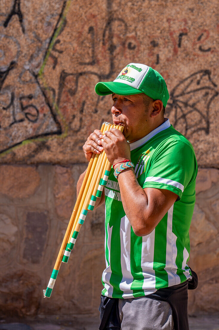 An indigenous man plays the siku panpipes plays for a religious procession in front of the church in Tilcara, Argentina.