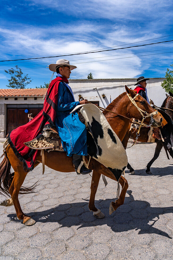 Gauchos in traditional outfits riding on horseback in a parade in Cachi, Argentina. Cowhide guardemontes protect the rider from thorn bushes common in the area.