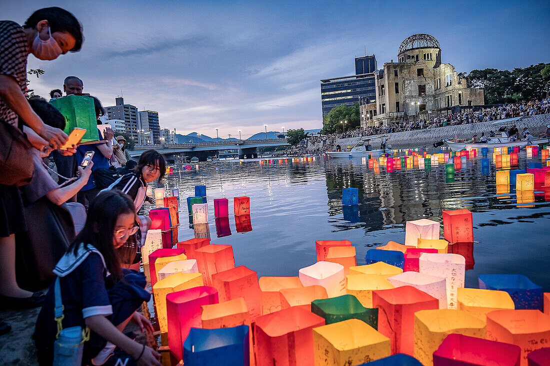 Menschen schwimmen mit Laternen auf dem Fluss, vor der Atombombenkuppel mit schwimmenden Lampen auf dem Motoyasu-gawa Fluss während der Friedensgedenkfeier am 6. August in Hiroshima, Japan