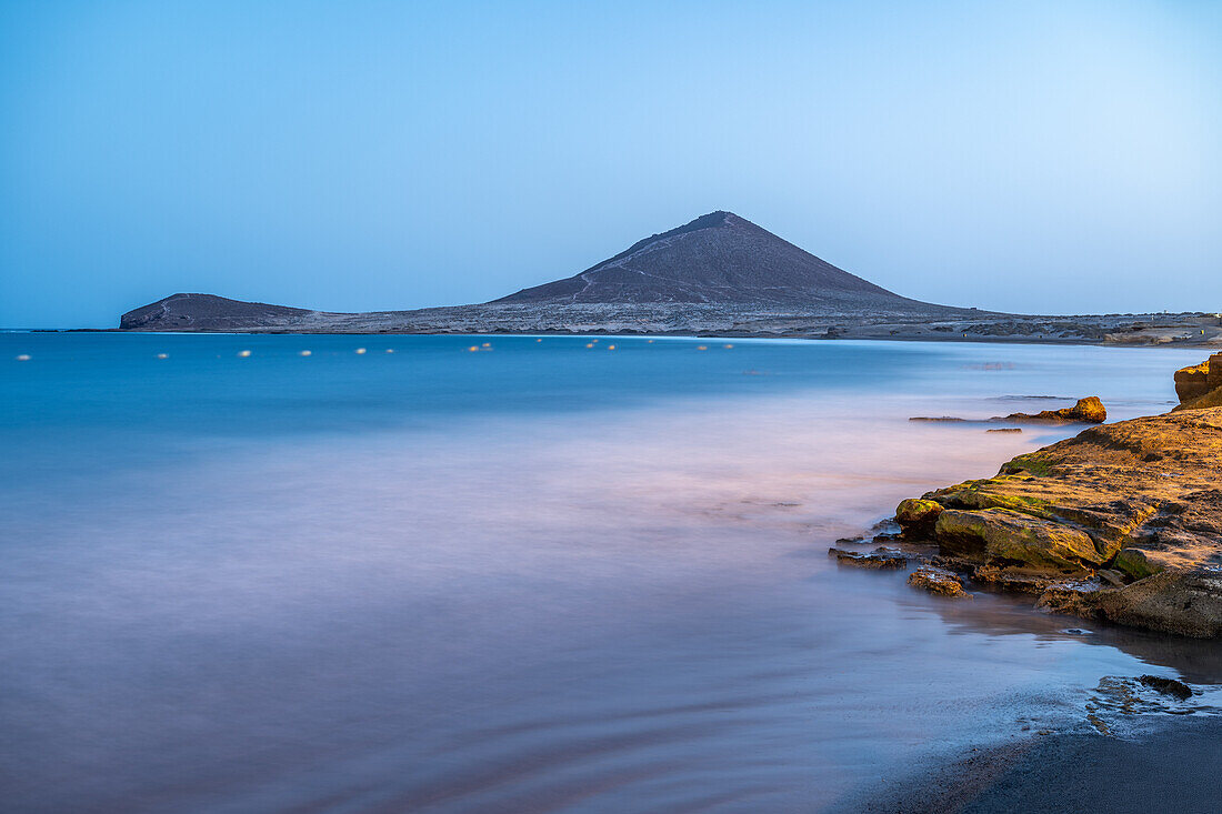 Langzeitbelichtung von Costa de El Medano mit Montana Roja im Hintergrund während der Dämmerung, Granadilla de Abona, Teneriffa, Kanarische Inseln, Spanien