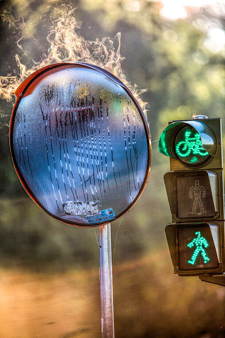 Morgentau verdunstet auf einem konvexen Spiegel neben einer Verkehrsampel in Sevilla, Andalusien, Spanien, und erzeugt einen einzigartigen visuellen Effekt