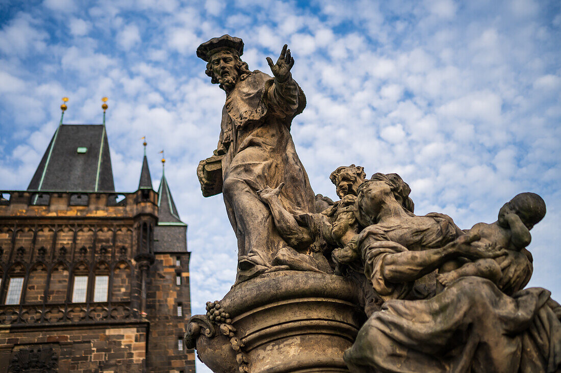 Statue des Heiligen Ivo von Kermartin und alter Turm an der Karlsbrücke in Prag