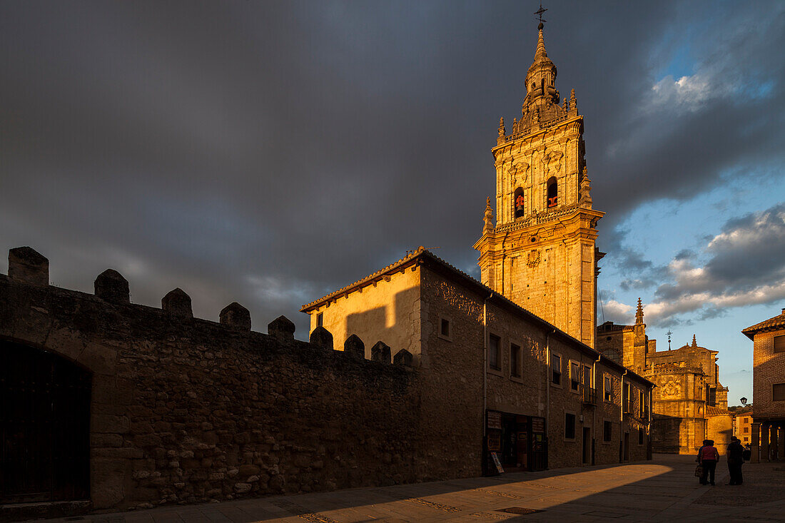 The Cathedral in El Burgo de Osma gleams in the warm glow of sunset, surrounded by historic architecture and dramatic skies.