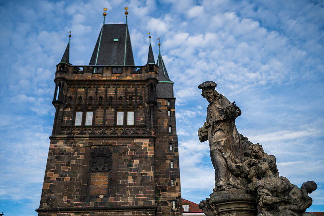 Statue des Heiligen Ivo von Kermartin und alter Turm an der Karlsbrücke in Prag