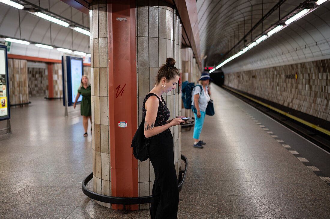 Menschen benutzen ihr Smartphone, während sie auf dem Bahnsteig der Prager U-Bahn warten