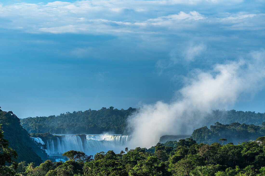 A plume of mist rises from the Devil's Throat or Garganta del Diablo at sunrise at Iguazu Falls National Park in Argentina. A UNESCO World Heritage Site. Brazil is on the left side of the canyon, with Argentina on the right.