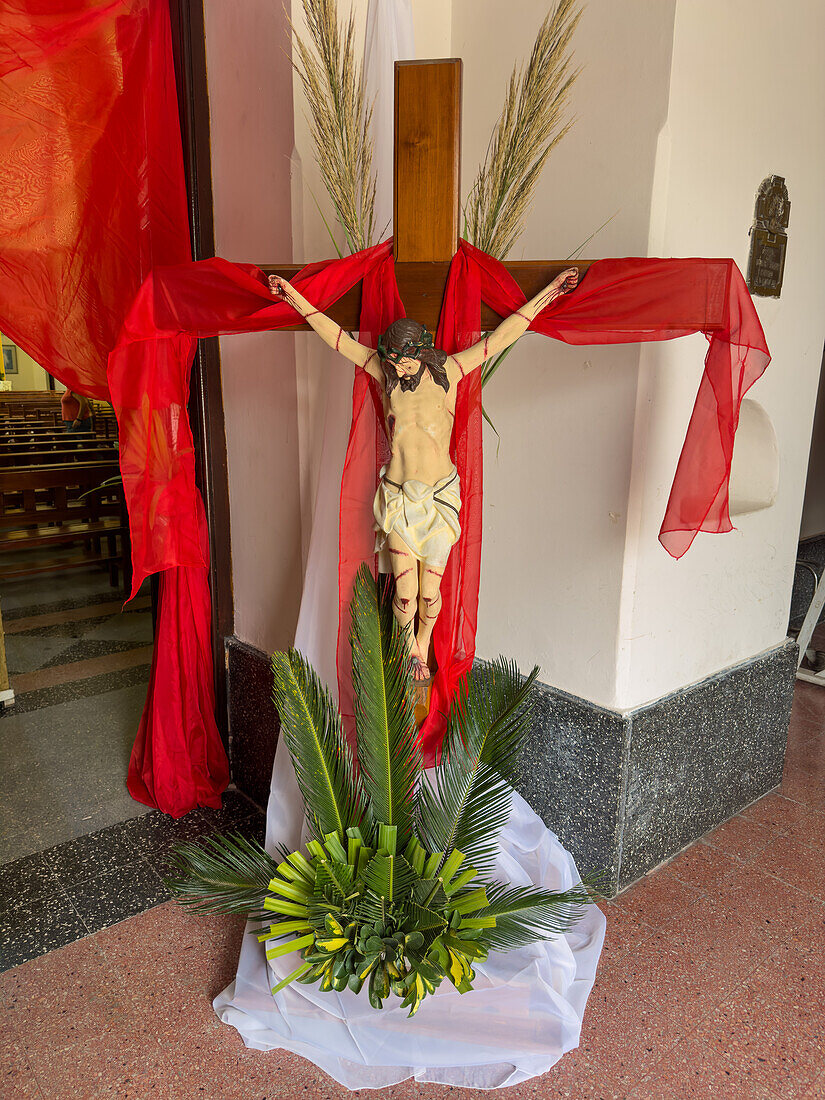 A statue of Christ on the cross at the entrance of the Church of Our Lady of the Rosary, Monteros, Argentina. Decorated with palm leaves for Palm Sunday.