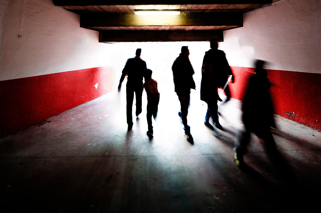 Fans are walking through a vomitorium towards a football match at a stadium in Seville, creating an energetic atmosphere on game day.