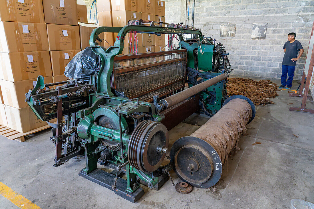 An older-style vintage powerloom no longer in use at Hilandería Warmi, a weaving mill in Palpalá, Argentina. Note the large bobbin of yarn by the machine.