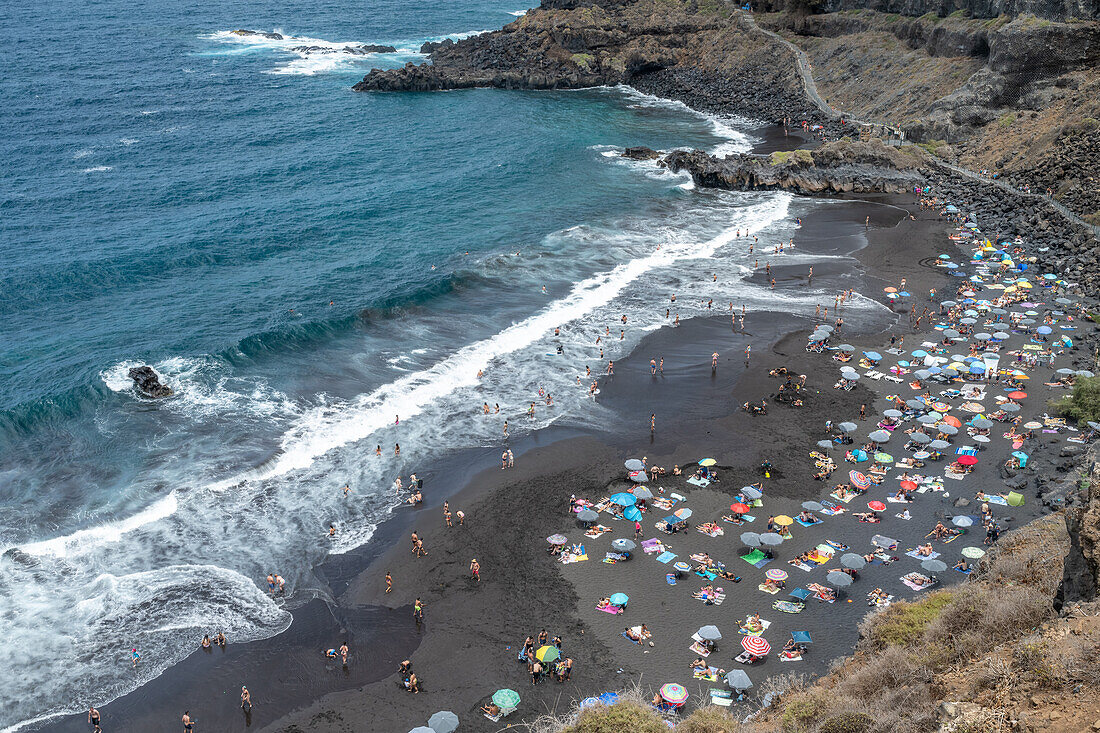 Ein malerischer Blick auf die Playa del Bollullo an der Nordküste Teneriffas in La Orotava mit schwarzem Sand, blauem Meer und Strandbesuchern