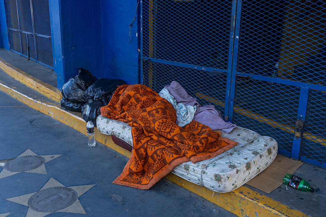 Ein Obdachloser schläft auf einer Matratze auf den Stufen des Stadions La Bombonera in La Boca, Buenos Aires, Argentinien