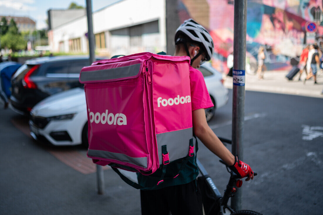 Junger Lieferjunge auf einem Fahrrad bei der Arbeit für Foodora in Prag, Tschechische Republik