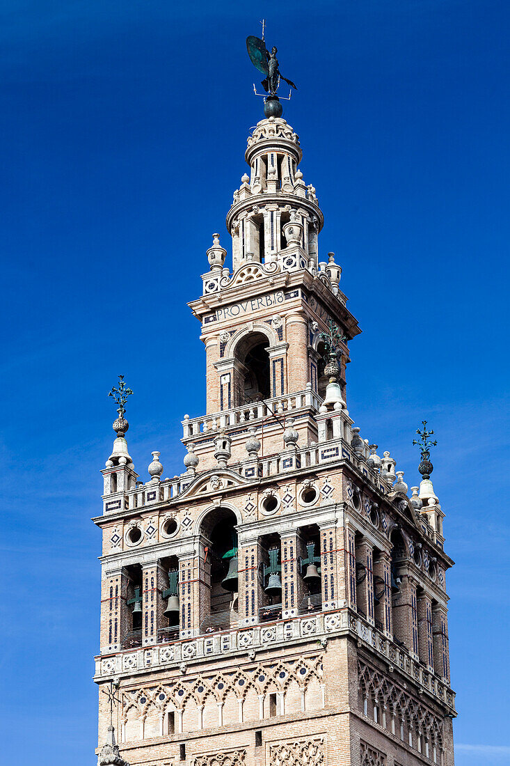 The Giralda tower stands majestically, showcasing its intricate architecture against a brilliant blue sky in Seville, Spain.