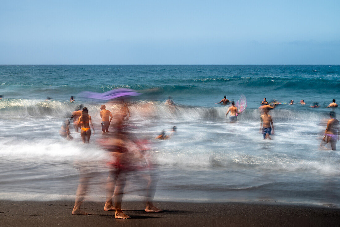 Langzeitbelichtung von Menschen, die die Wellen am Bollullo-Strand in La Orotava, Teneriffa, auf den Kanarischen Inseln genießen