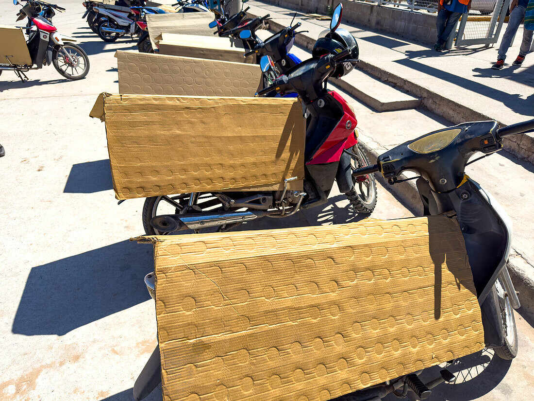 Folded cardboard protects the seats of parked motorcycles outside a shopping center in Tartagal, Argentina.