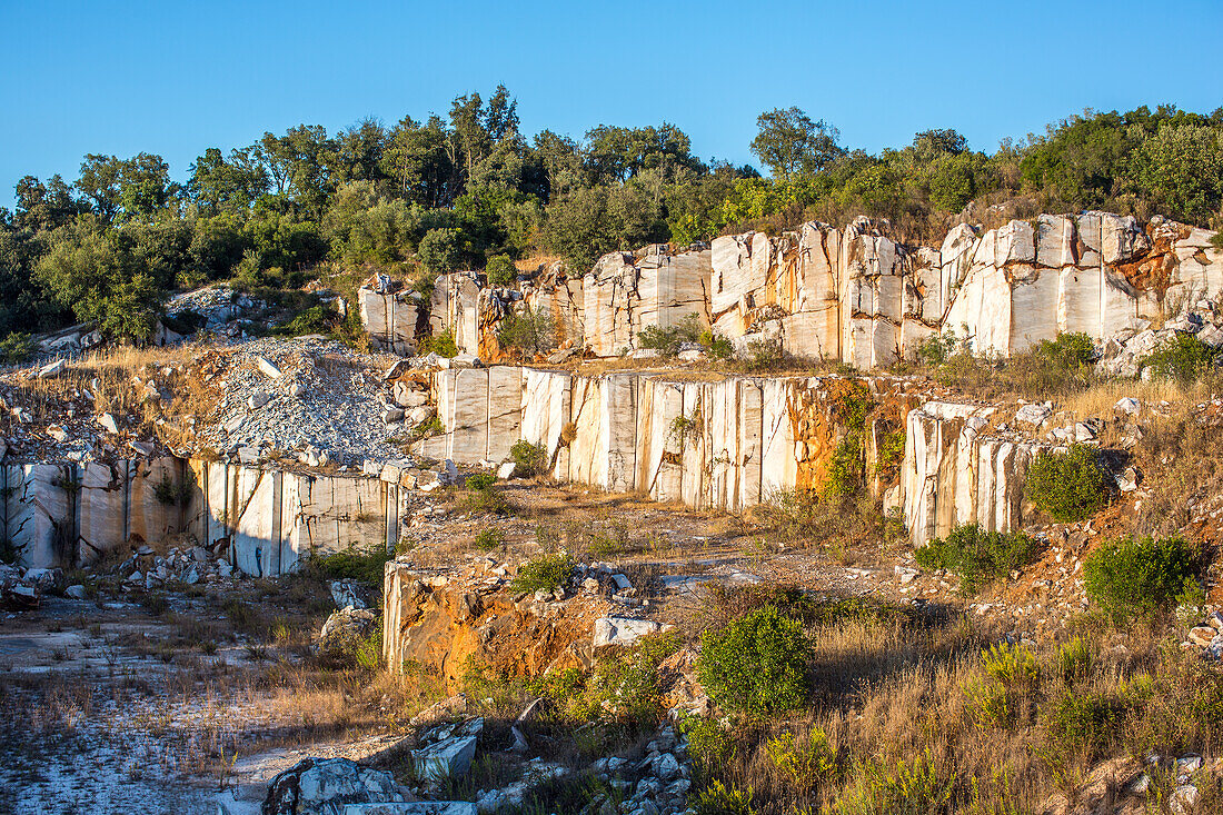 A scenic view of the abandoned marble quarry in Fuenteheridos, Huelva province, Andalusia, Spain. The overgrown vegetation adds a touch of nature to the industrial landscape.