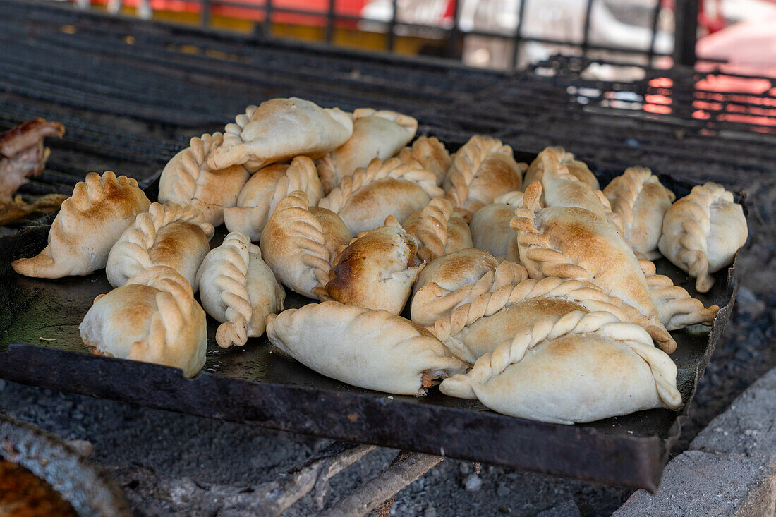 Fresh-baked empanadas on a tray over coals to keep them hot in a traditional parrilla in Termas de Rio Hondo, Argentian.