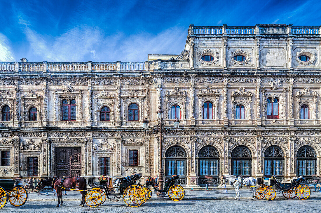 Kutschen warten vor der verschnörkelten plateresken Fassade des Rathauses von Sevilla, einem Beispiel für historische Architektur im pulsierenden Andalusien