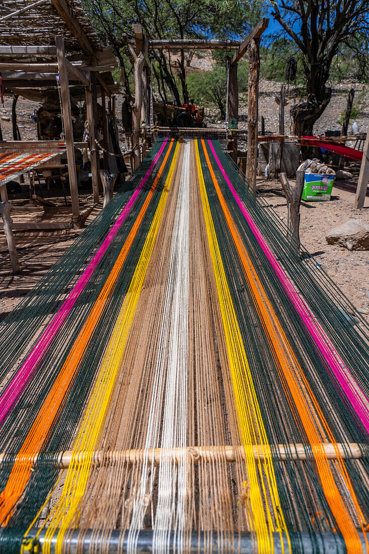 Buntes Garn auf einem hölzernen Fußwebstuhl in einer Heimweberei in Seclantas, Argentinien im Calchaqui-Tal