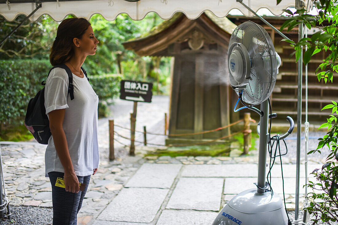 Frau erfrischt sich mit einem Ventilator in Kyoto