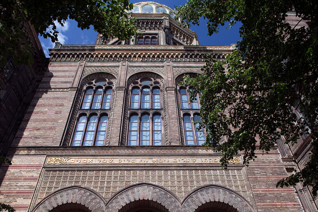 The New Synagogue in Berlin showcases stunning Moorish architecture on Oranienburger Strasse surrounded by lush greenery.