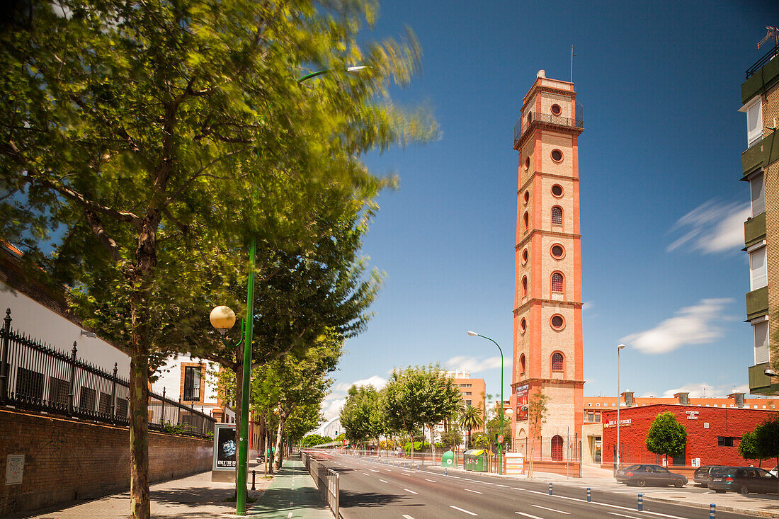 The Torre de los Perdigones illuminated against the skyline, captured in a long exposure showing motion amidst a quiet street.