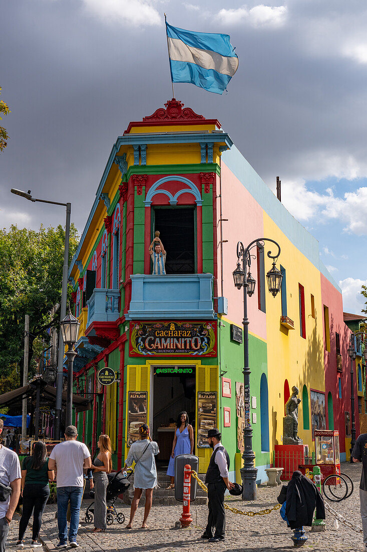 A tourist poses for a photo on Caminito Street in La Boca, Buenos Aires, Argentina.