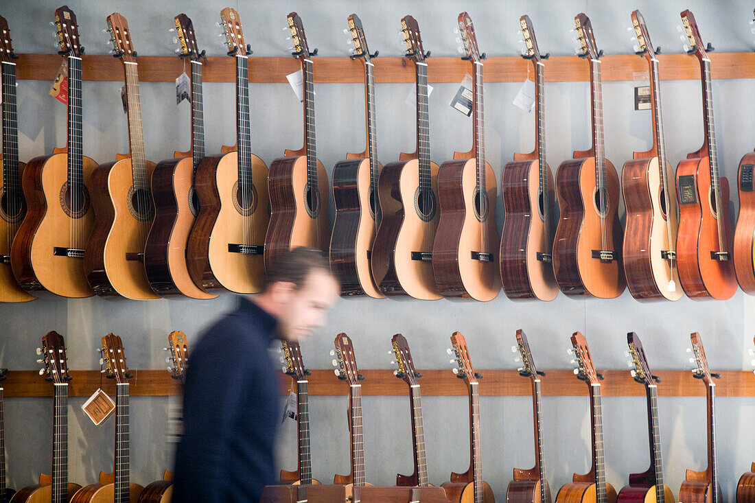 Sevilla, Spanien 13. Januar 2007, An der Wand eines Musikgeschäfts in Sevilla sind verschiedene Gitarren ausgestellt, während im Vordergrund ein Mann vorbeigeht