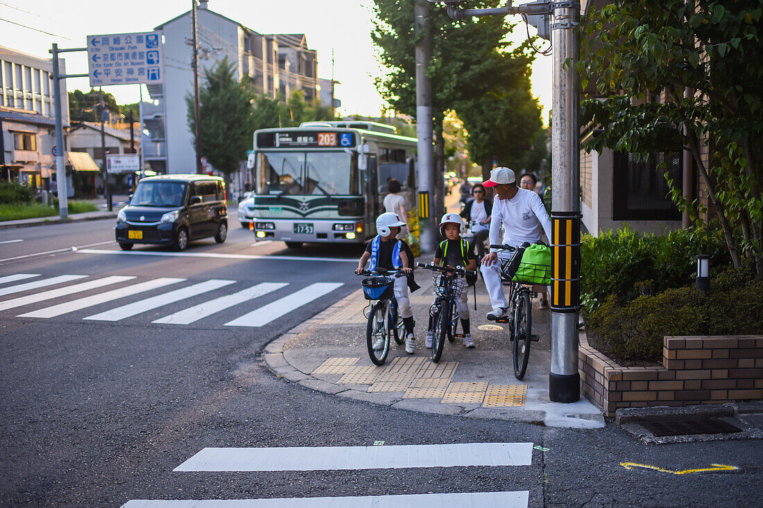 Kids on bikes waiting to cross a street of Kyoto, Japan