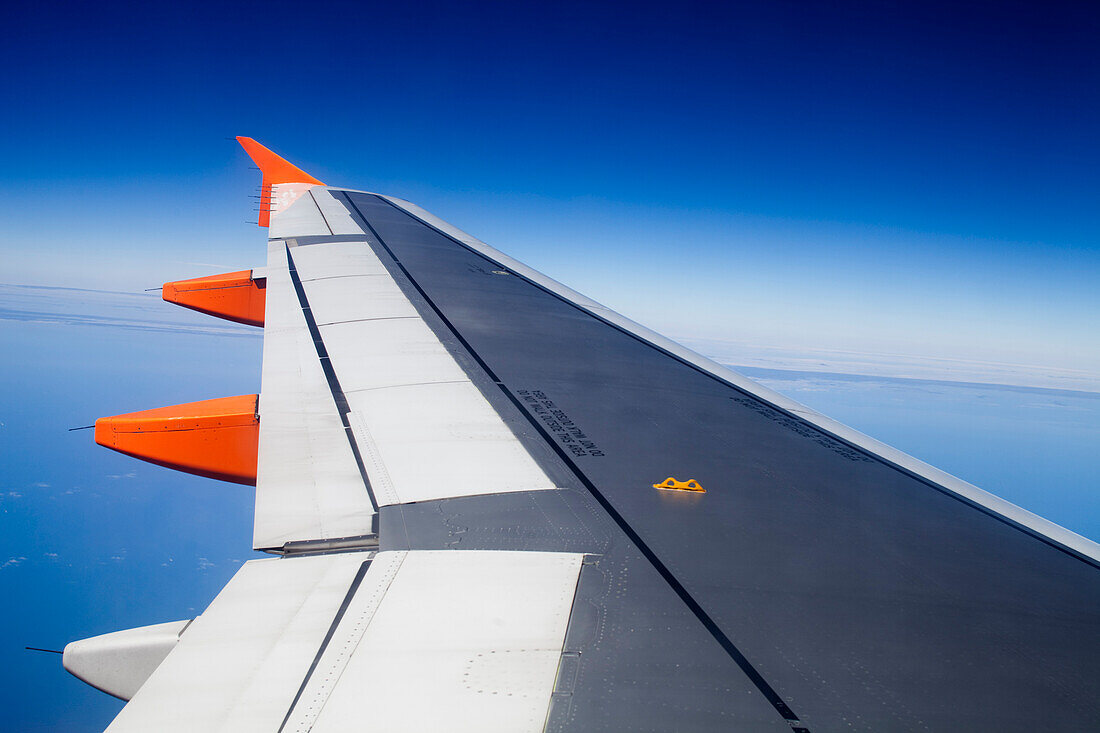 A wing stretches over the vast blue expanse, showcasing a view of Portugal from an aircraft.