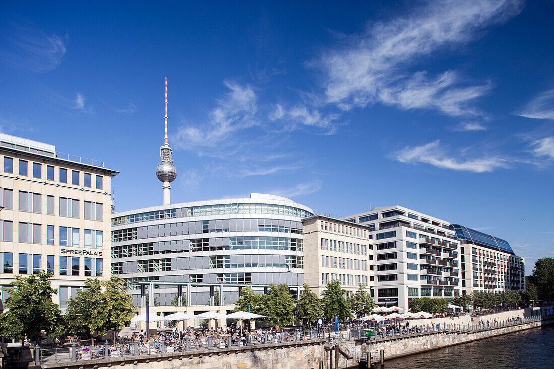 Contemporary buildings line the East bank of the Spree river, showcasing Berlin\'s vibrant architecture and the iconic television tower.