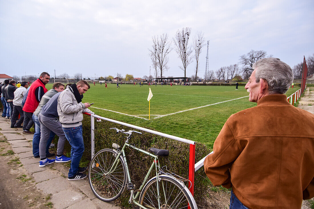 People watching a soccer youth game in small town of Hungary