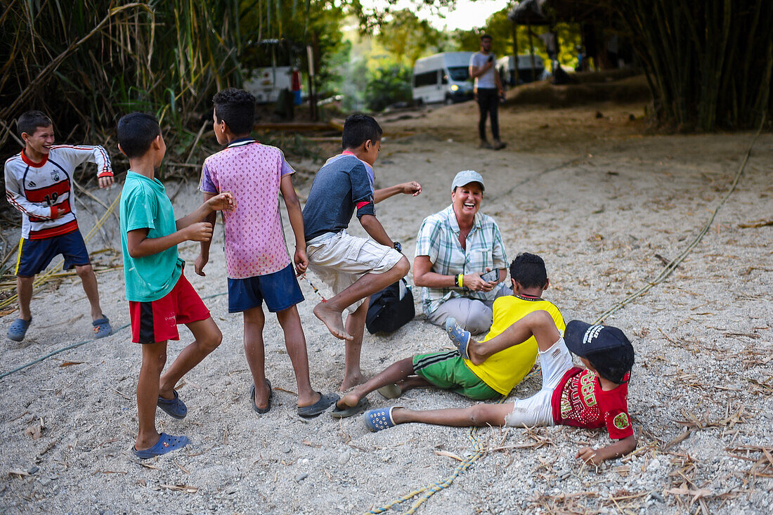 Eine Gruppe verspielter einheimischer Kinder hat Spaß mit einer Ausländerin, Santa Marta, Kolumbien