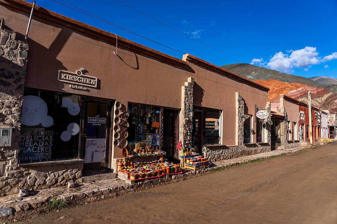 Geschäfte und Restaurants entlang der Calle Libertad in Purmamarca, Argentinien, mit dem Berg der sieben Farben rechts im Hintergrund