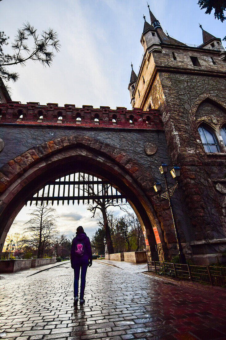 Young woman entering the gate of Vajdahunyad Castle, Budapest, Hungary