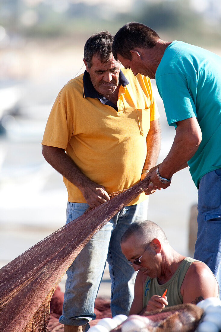 Seville, Spain, Aug 7 2008, Fishermen work together to mend their fishing nets at Bonanza port in Sanlucar de Barrameda, Cadiz region of Spain.