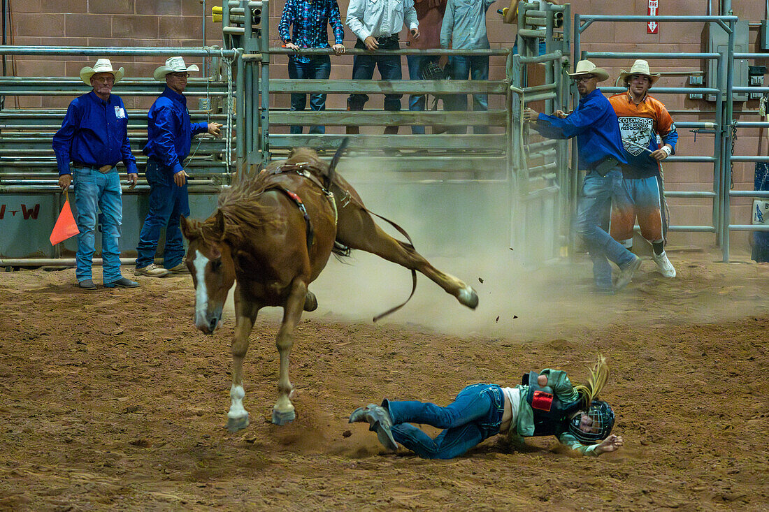 Ein junges Cowgirl wird beim Moab Junior Rodeo in Moab, Utah, von einem bockenden Pferd gestoßen. Man beachte, dass ihr ein Arm fehlt