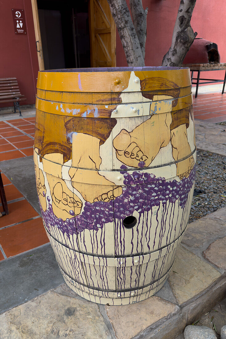 Painted wine barrel in the courtyard of the Museo de la Vid y el Vino or Museum of the Vine and the Wine in Cafayate, Argentina. The painting has a wine-making motif.